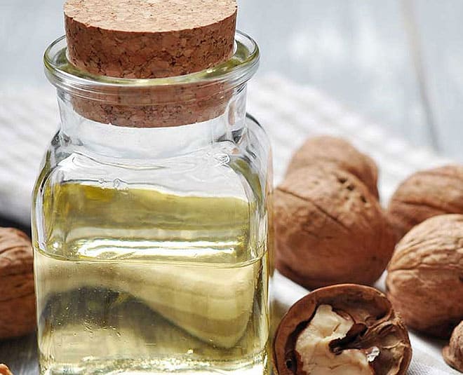 A jar of cold-pressed walnut oil beside whole walnuts